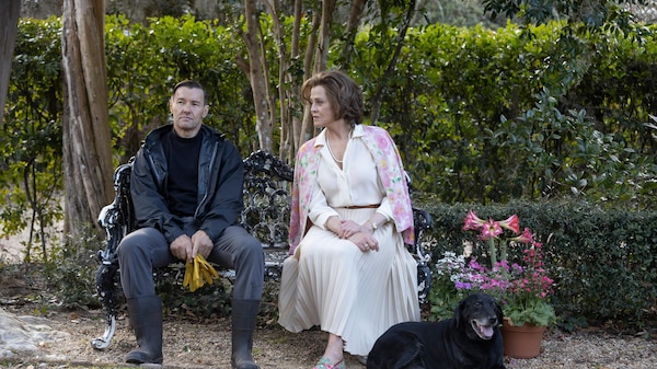 Man and woman sit on a seat in a garden.