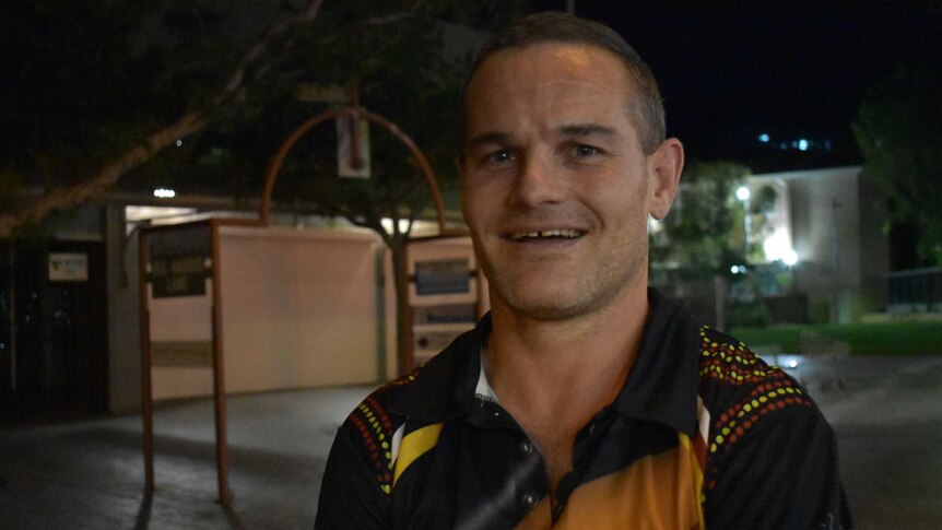 Nathan Coelli smiles at the camera. His hair is short and it is night time in Alice Springs.