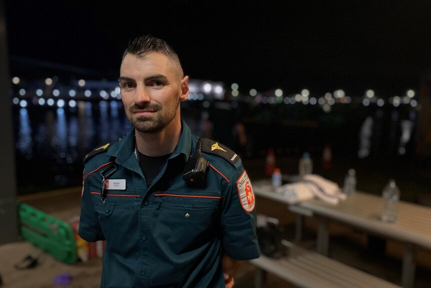 St John's paramedic Geordie Aulich stands in front of the Darwin Waterfront at night.