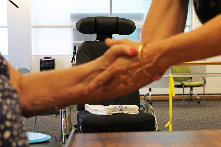 A photo of a wheelchair in front of Eileen's arm being stretched.