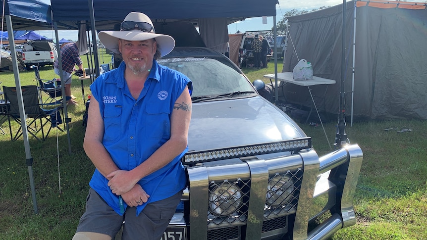 A man smiles, as he sits on the bonnet of his modified ute.