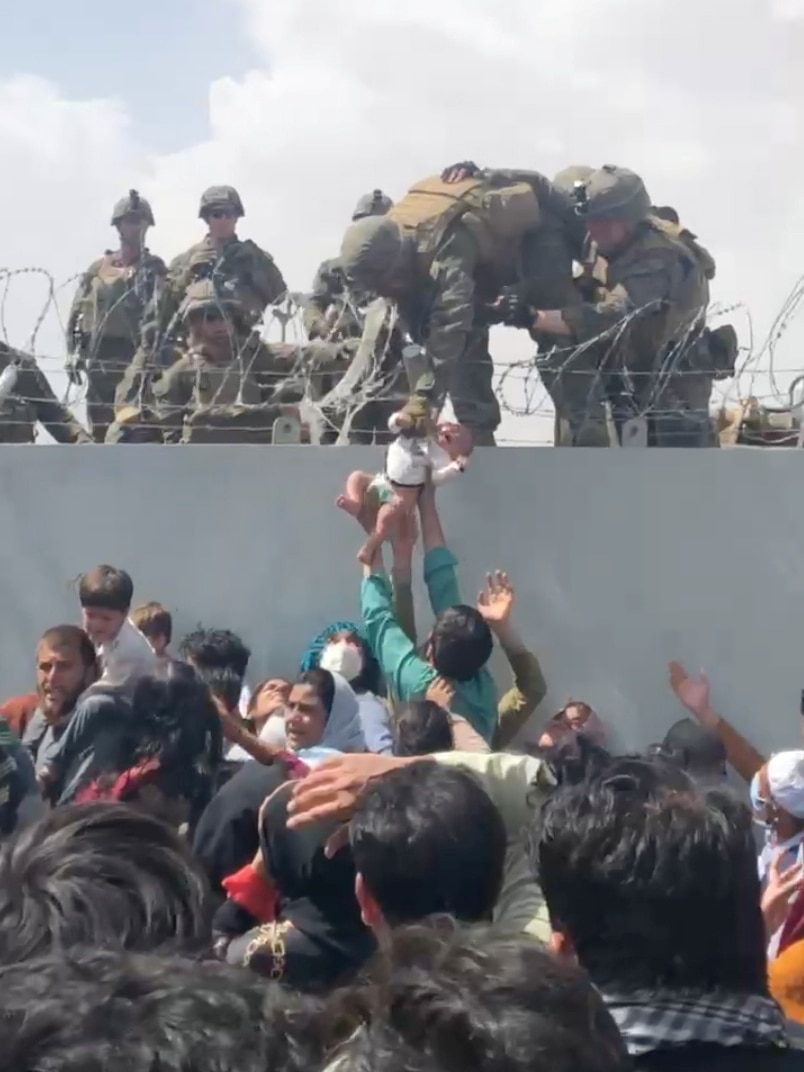 A baby is lifted to American soldiers.