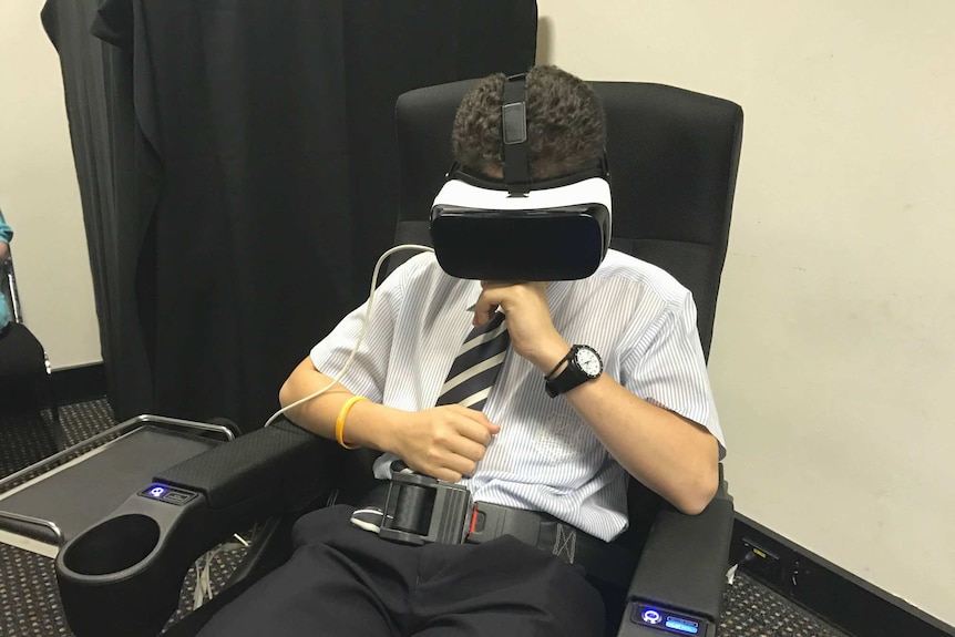 A student sits in a chair with a virtual reality headset on