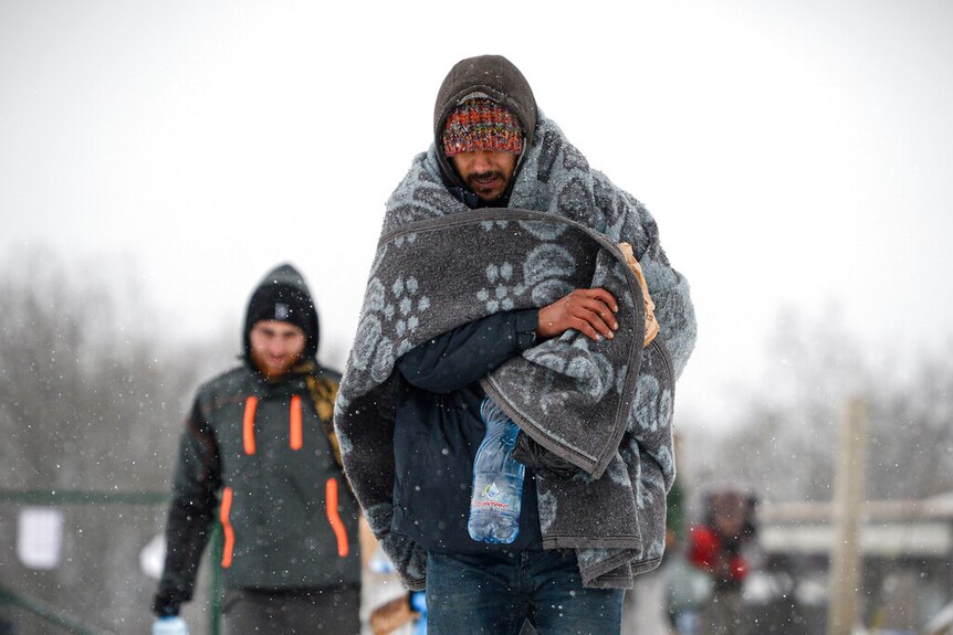 Migrants walk through the snow at the Lipa camp north-western Bosnia, near the border with Croatia.