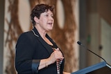 Jackie Jarvis from the RRR Women's Network of Western Australia speaks at a podium at the #UsToo lunch event in Perth