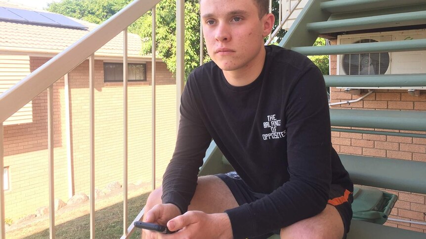 Christian Berndt sits on the stairs of his house with his phone in his hands