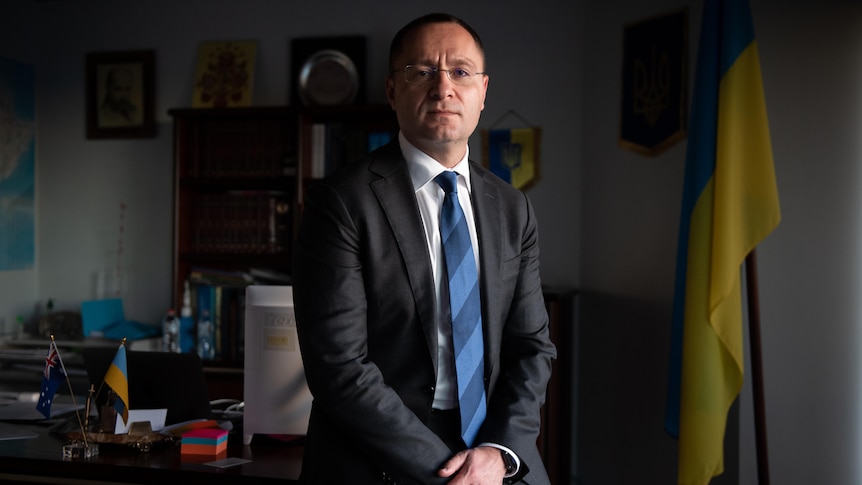 A man wearing glasses, standing in front of a desk