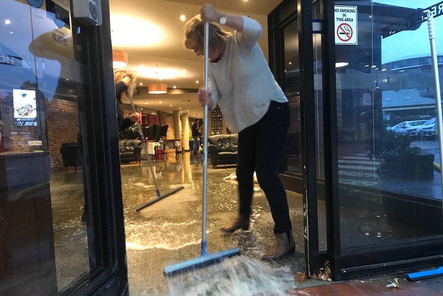 People sweeping floodwaters out of a central Hobart shop