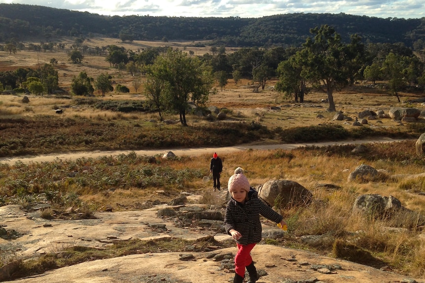 Children running in a mountain paddock looking for snow.