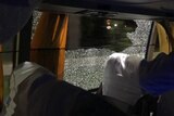 A shattered window is seen from inside the bus