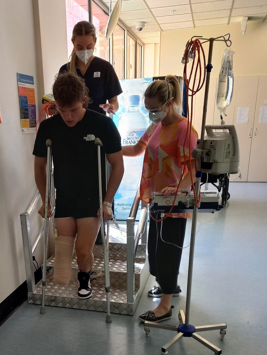 A teenage boy with a leg amputation is on crutches, learning to walk. 