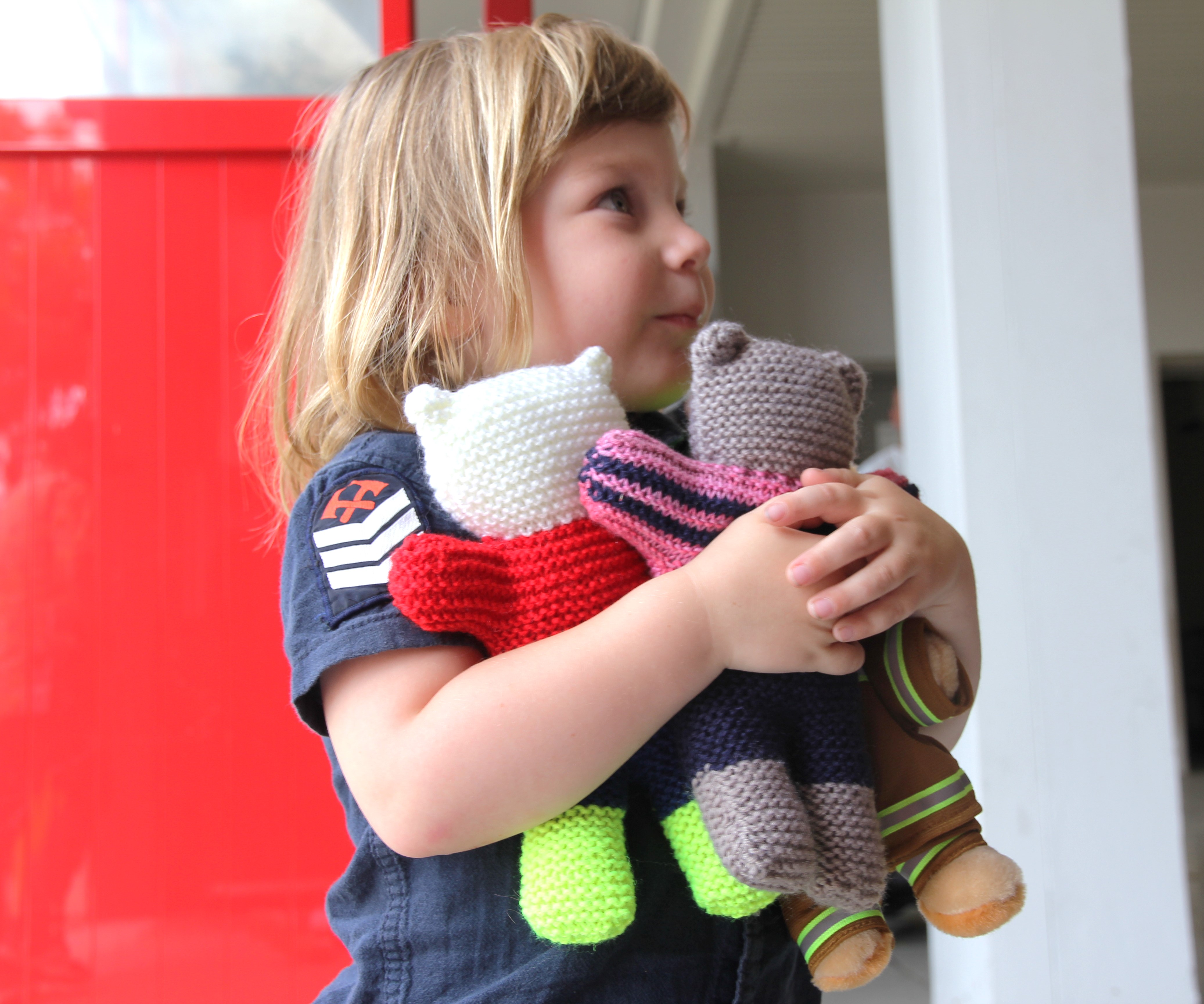Liam Moffitt hugging three coloured teddy bear toys