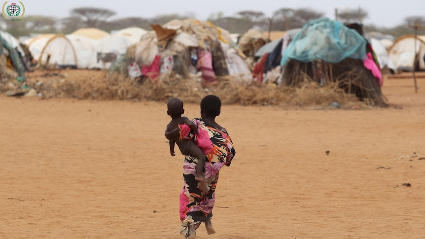 A young girl carries a naked child at a refugee camp in Kenya