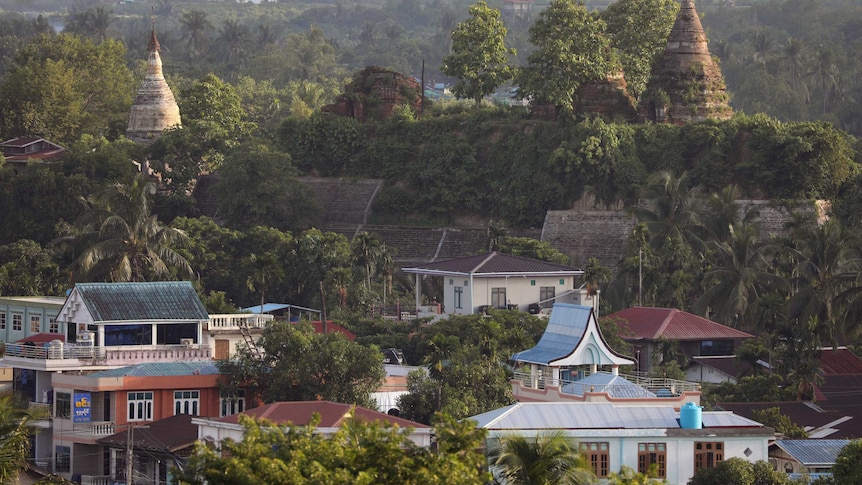 A landscape view of trees, houses, huts and pagodas.