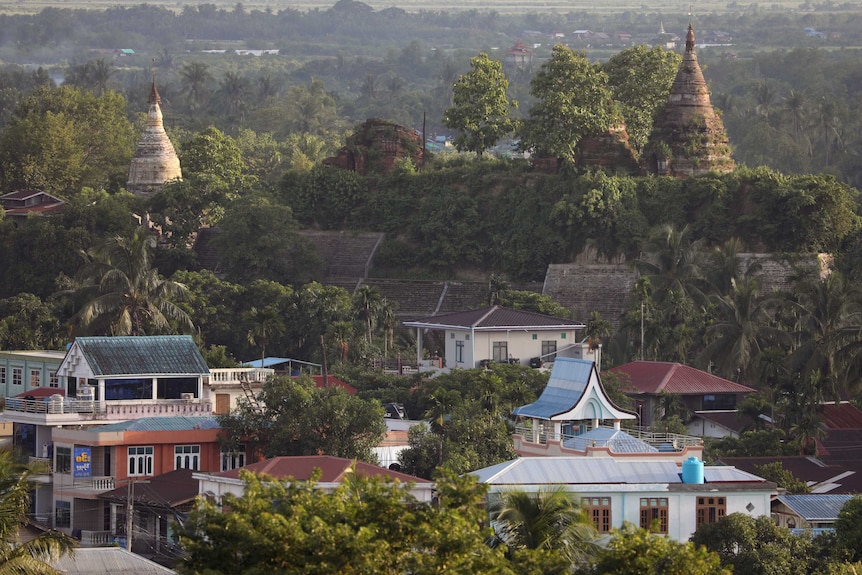 A landscape view of trees, houses, huts and pagodas.