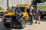Three men standing next to a new yellow rural fire Land Cruiser utility.