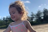 Nevaeh Austin on the beach, with curly hair and a jumpsuit.