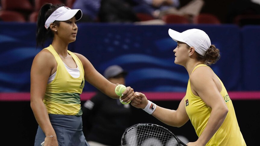 Two tennis players bump fists to celebrate winning a point in a doubles match.