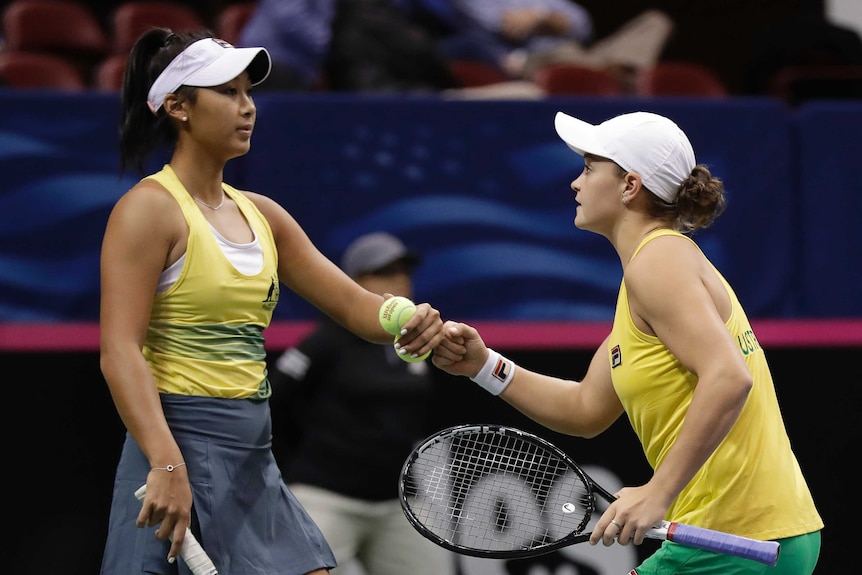 Two tennis players bump fists to celebrate winning a point in a doubles match.