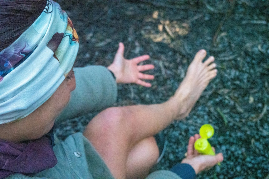 A woman bending over and looking a her sore feet.