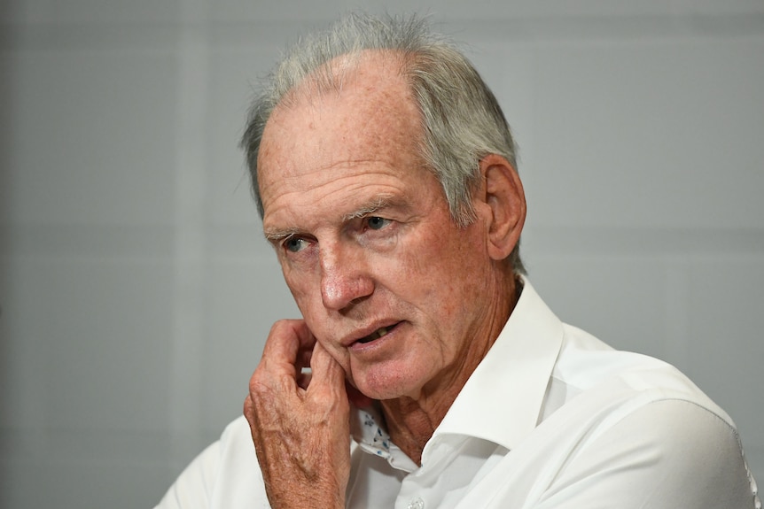 Wayne Bennett scratches his chin with a neutral expression on his face
