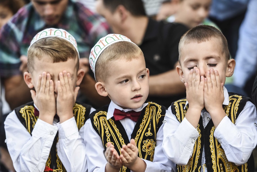 Young Kosovo Muslims take part in a prayer during a celebration of Eid al-Fitr