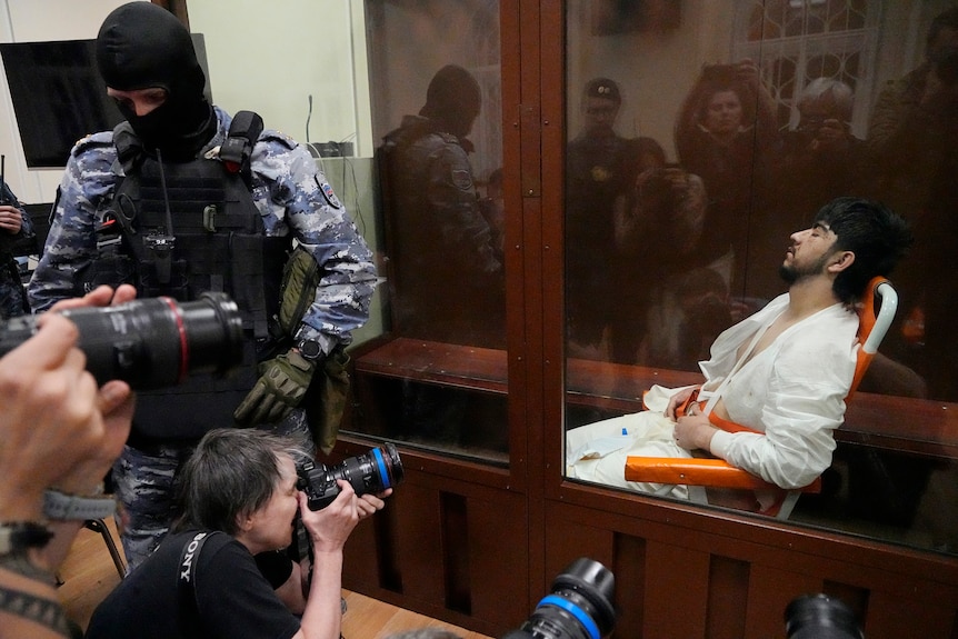 周五在莫斯科克洛克斯市政厅发生的枪击案的一名嫌疑人坐在莫斯科巴斯曼尼地区法院的玻璃隔间里。