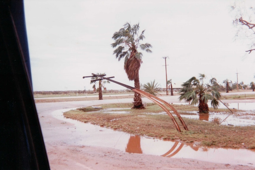 A metal telephone pole bent due to strong winds from a cyclone.