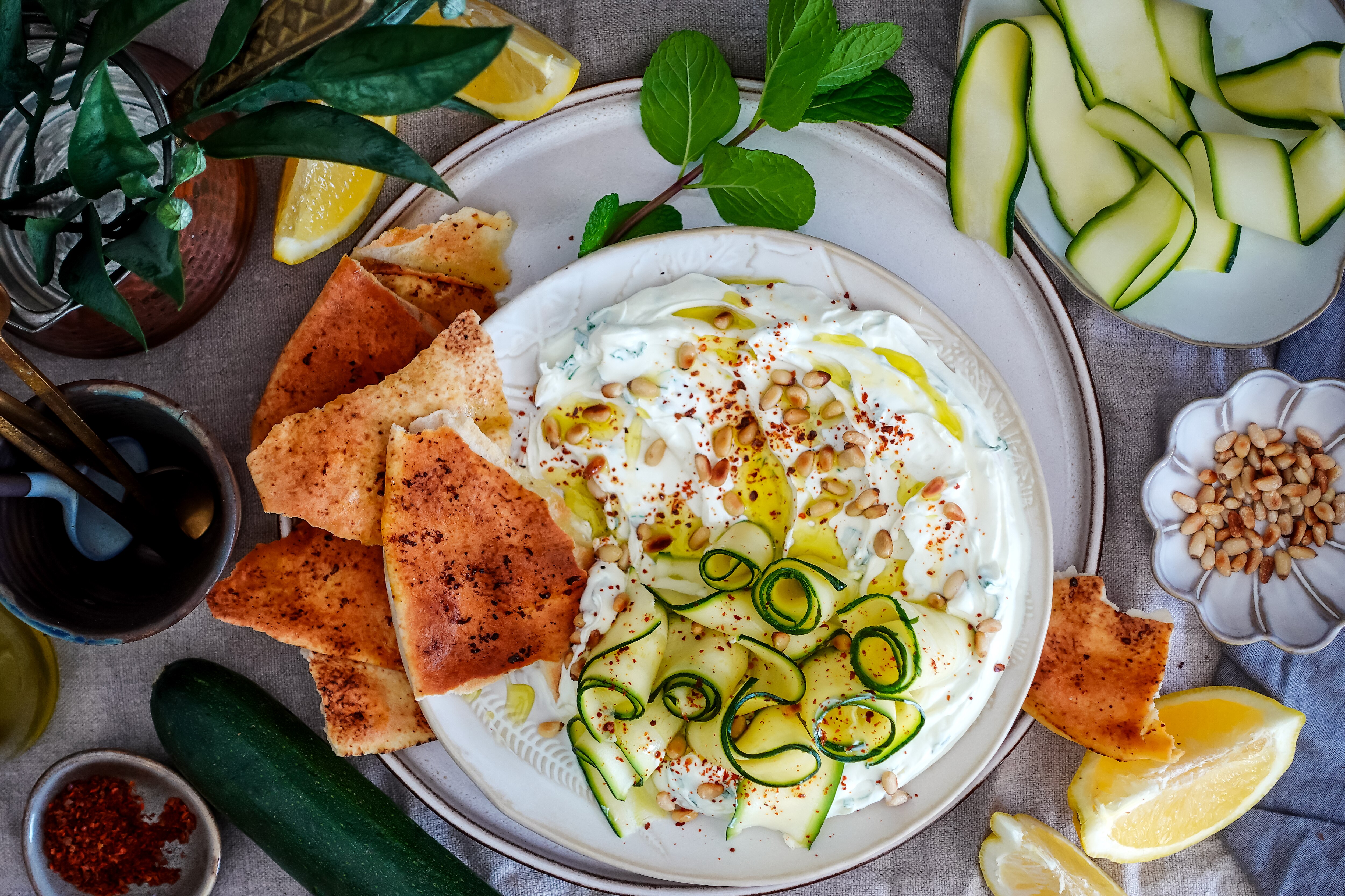 Un plato de labne con pan plano y tiras de calabacín, una ensalada sin cocinar para los días de calor.