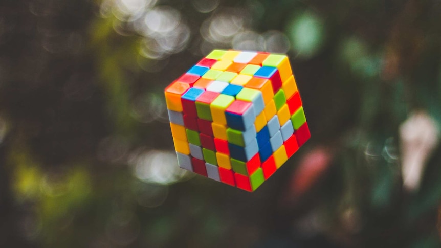 Colourful plastic mock-up of a rubix cube which has been thrown up into the air.