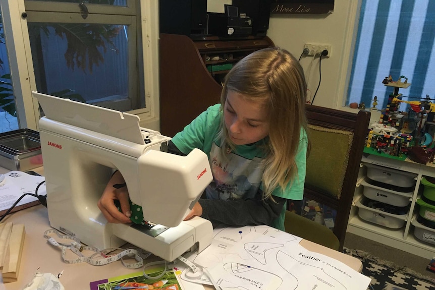 Amelia's son using a sewing machine