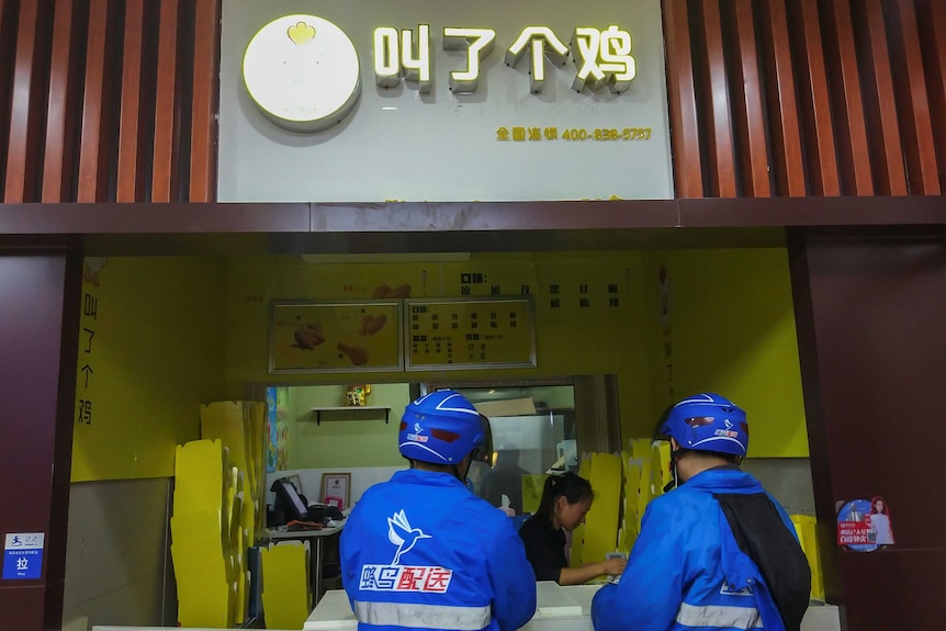 Deliverymen stand at the counter at a "Call a Chick" store in Shanghai.
