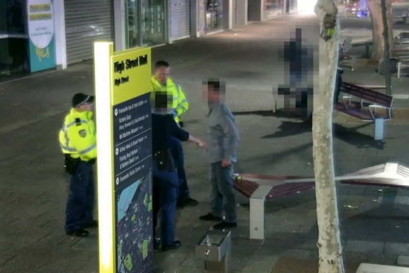 Several police officers speak to a man on a Fremantle street.