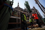 Workers secure a religious statue perched atop Paris' Notre Dame Cathedral.