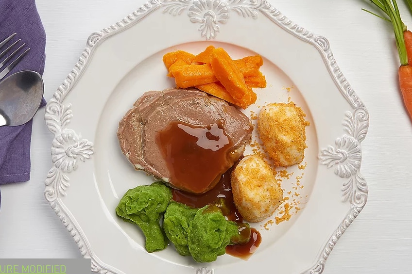 A photo of meat and vegetables on a plate.