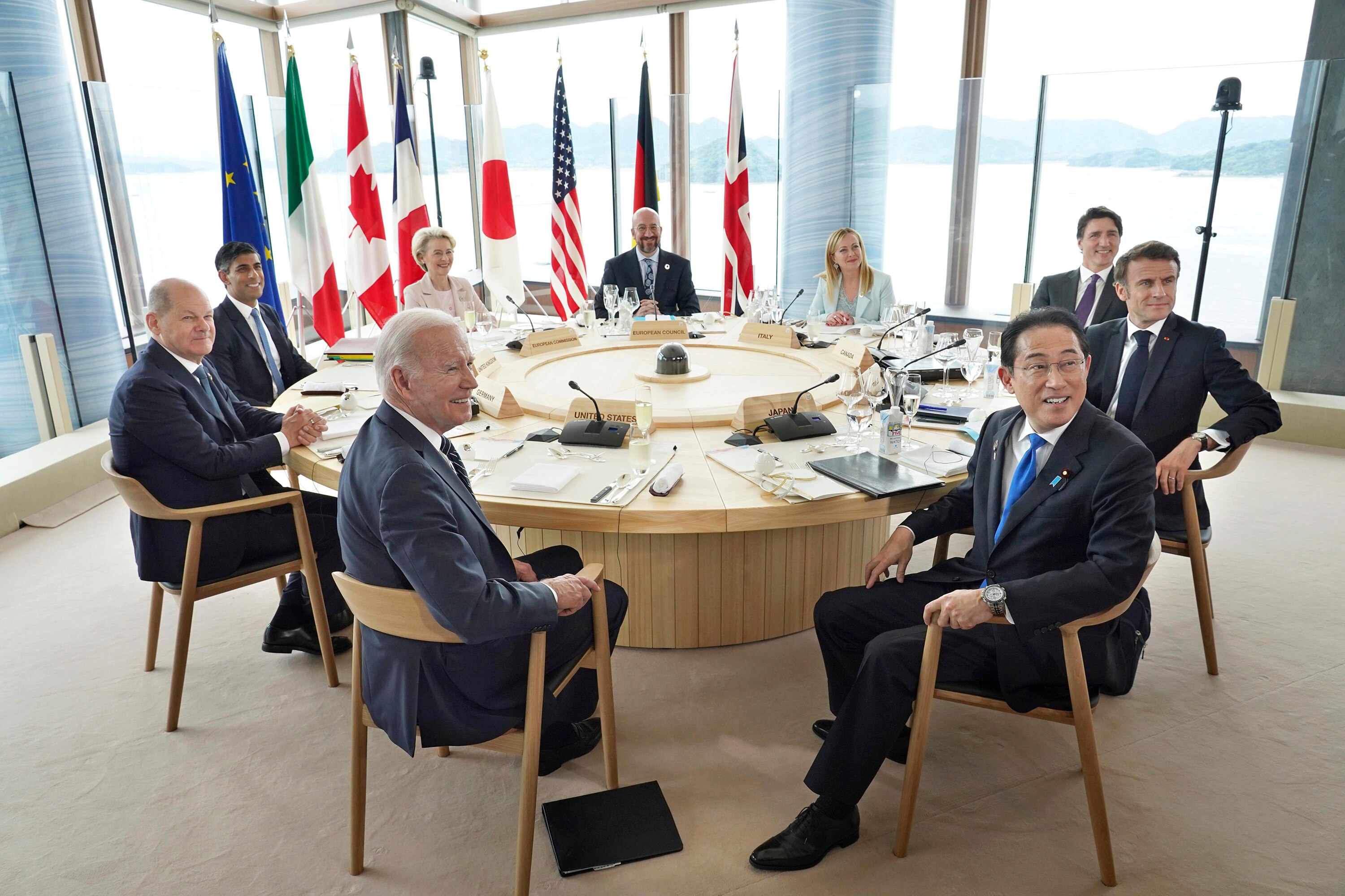 G7 nation leaders sit around a circular table and pose for photos.