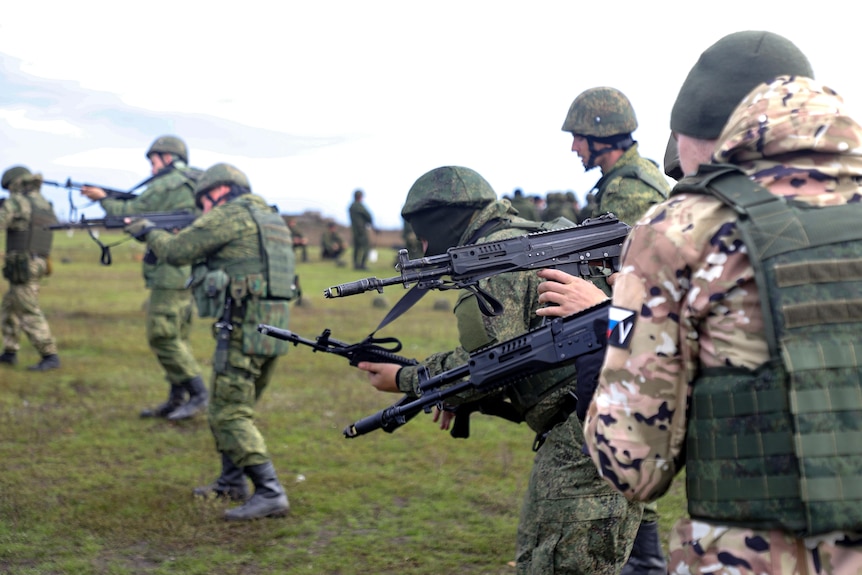recruits dressed up in army uniforms hold guns at a firing range in the Russian-controlled Donetsk region of Ukraine