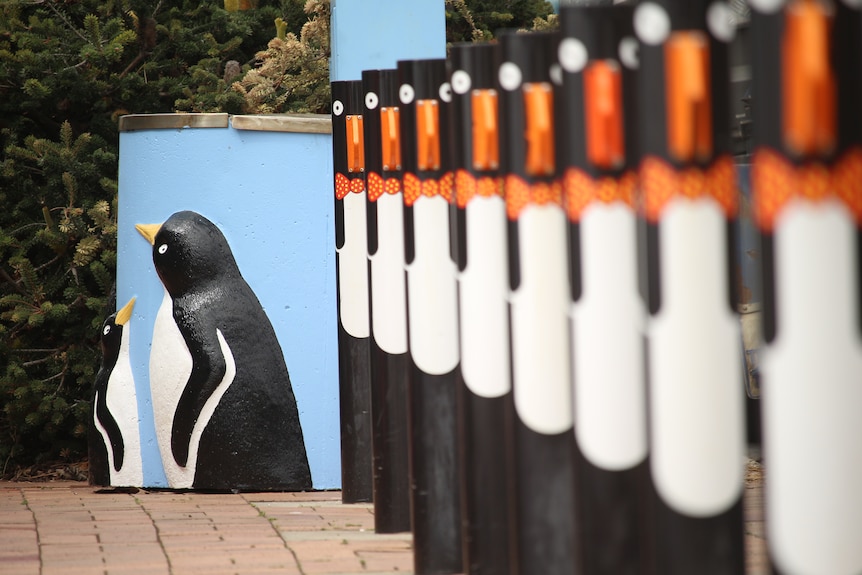 A blue bin with two penguins painted on the side