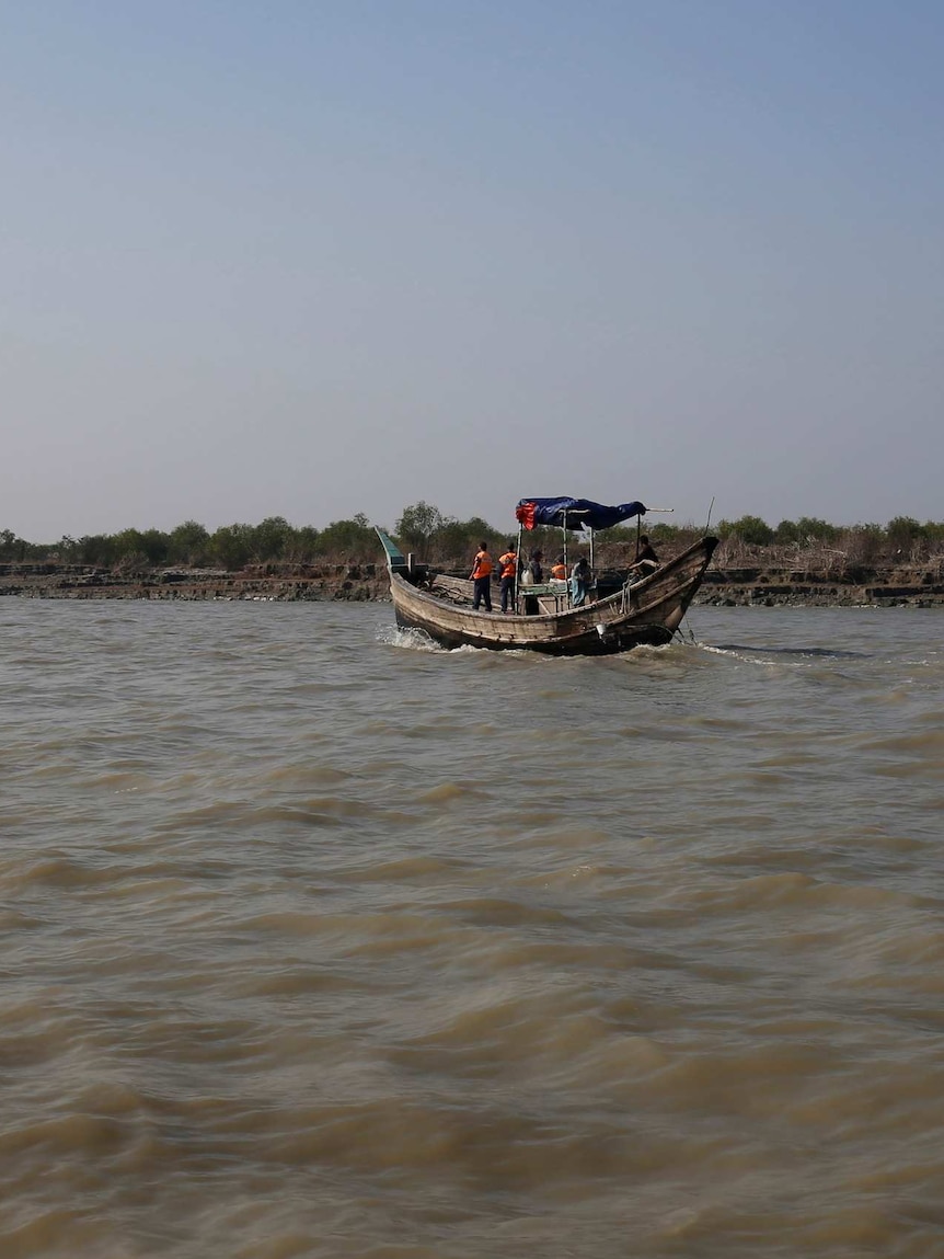 Bangladeshi coast guard vessel sails past a muddy land bank
