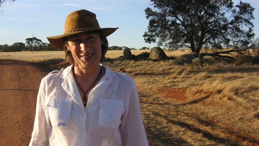 Susi Elizabeth Johnston wearing an Akubra and standing on a gravel road in the bush.
