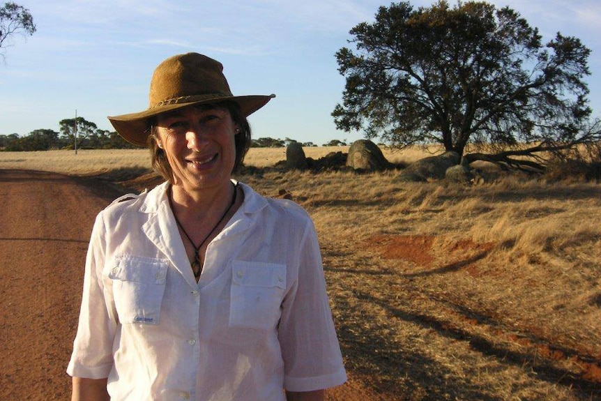 Susi Elizabeth Johnston wearing an Akubra and standing on a gravel road in the bush.