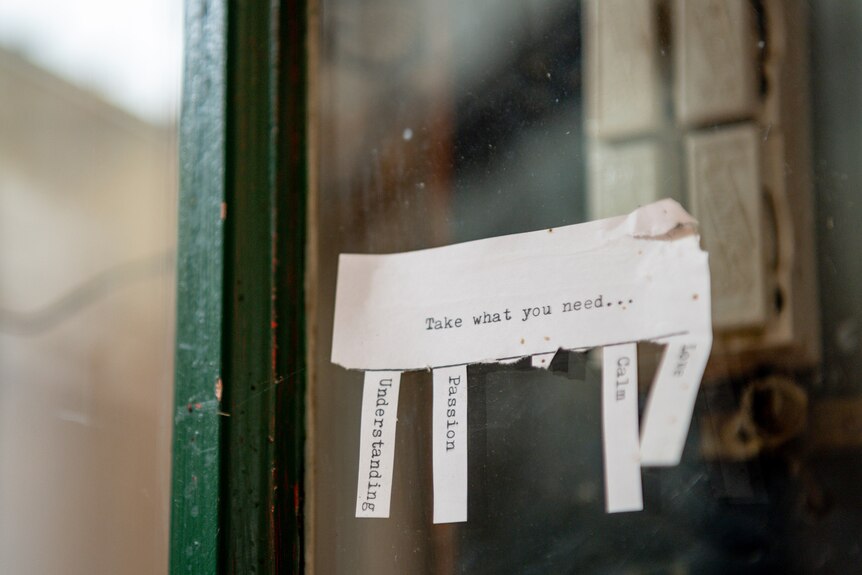 A sign in the window of a store in Terang reading "Take what you need" with tear-off strips about emotions.