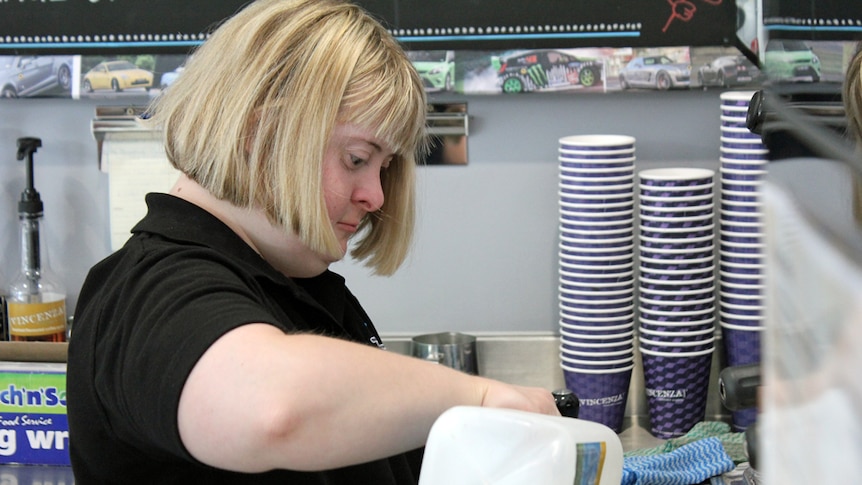 Trainee pours milk at the coffee machine.