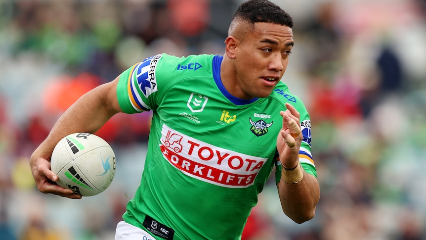 A man runs the ball during a rugby league match