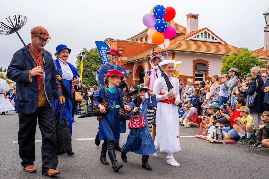 A group of people dressed as chimney sweeps, and Mary Poppins march in a parade.