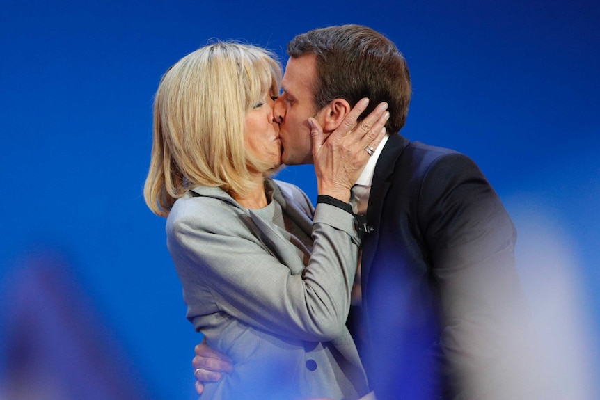 Emmanuel Macron and wife Brigitte share a kiss.