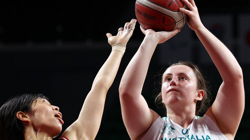 An Australian female wheelchair basketball players holds the ball in two hands as she prepares to shoot.