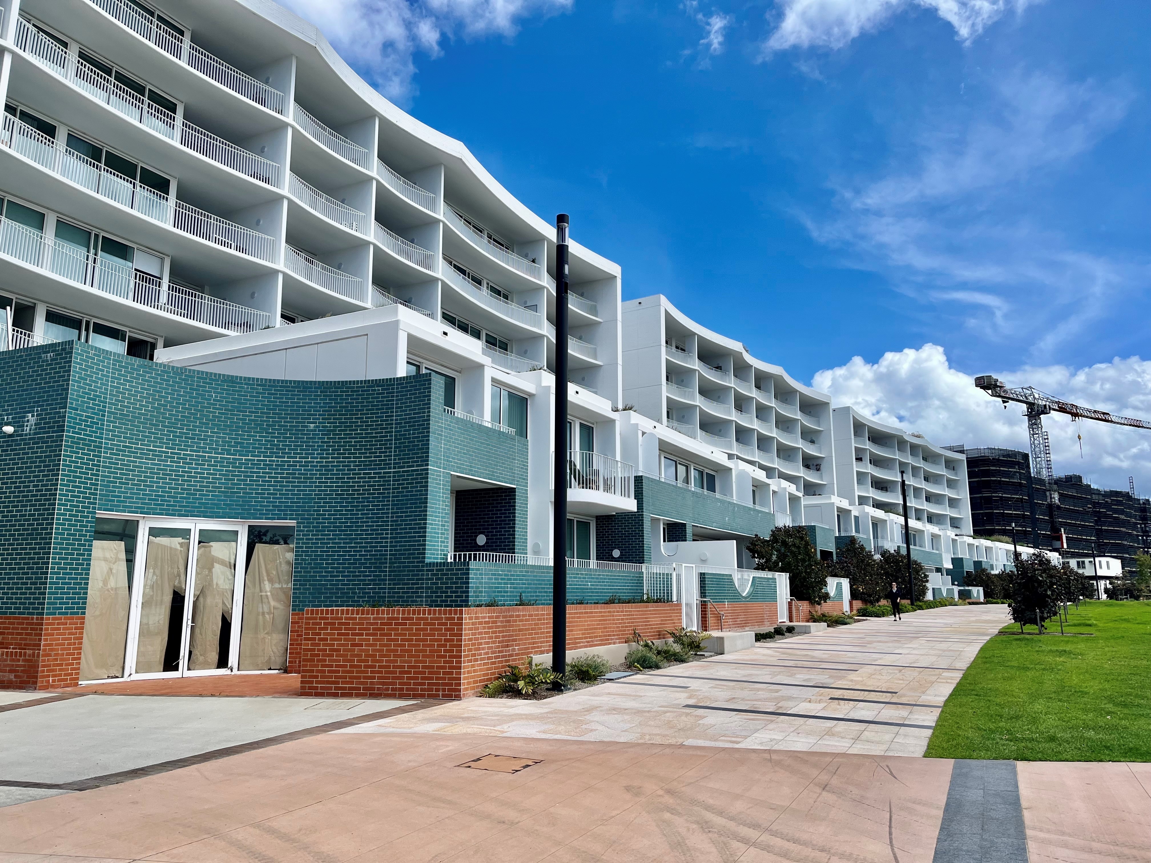 White and green apartment block with a footpath and green lawn out the front.&nbsp;