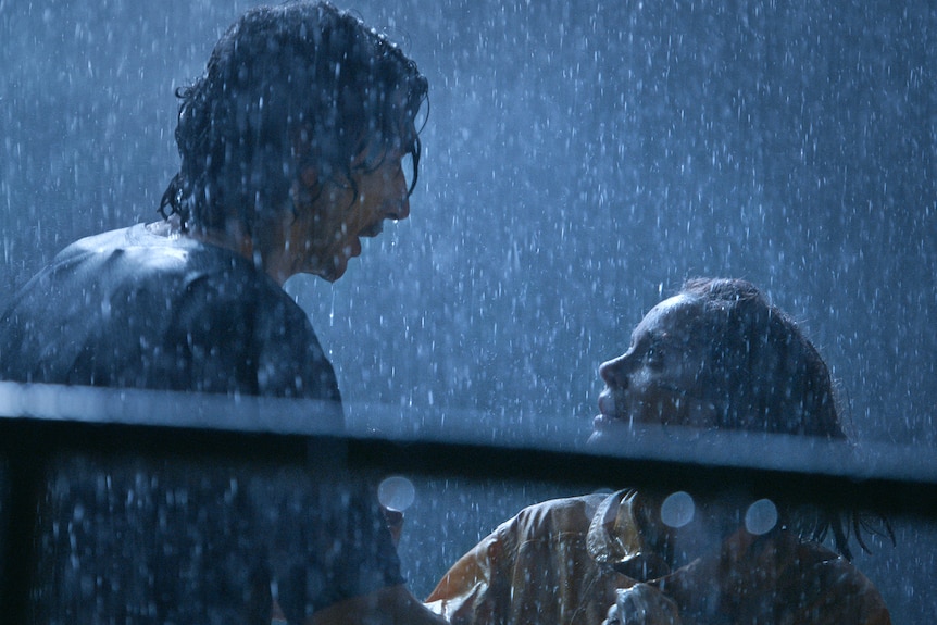 在柔和的蓝色月光下，亚当·德赖弗兴奋地抱着玛丽昂·歌迪亚。 两人都被雨淋湿了。