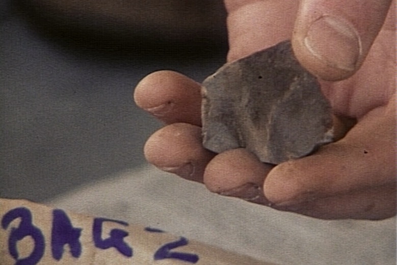 A hand holding a stone tool with a sharpened point that is thousands of years old.
